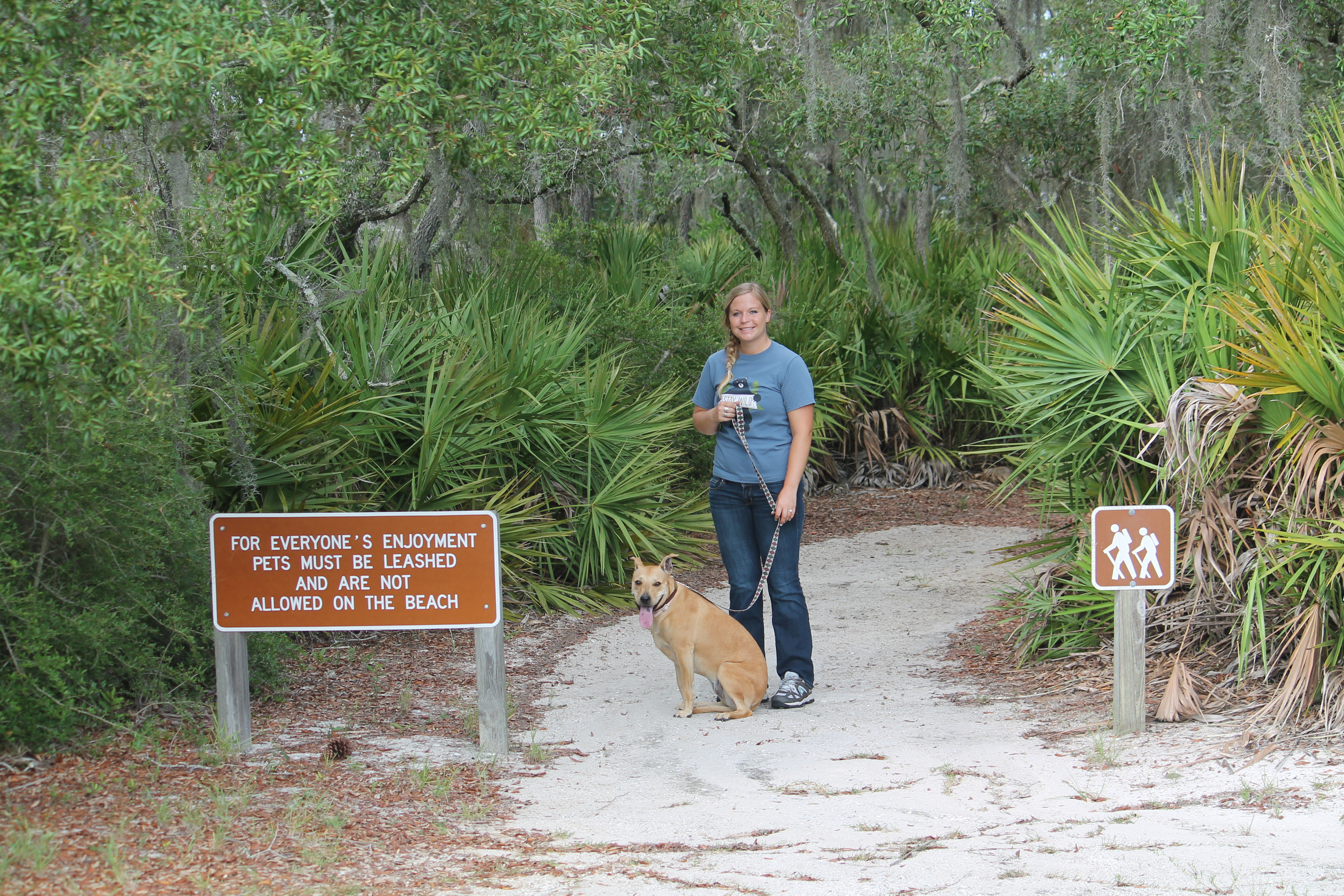 Girl standing with her dog on a leash getting ready to hike